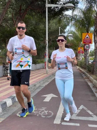 Two runners side by side on the red coastal bike path.