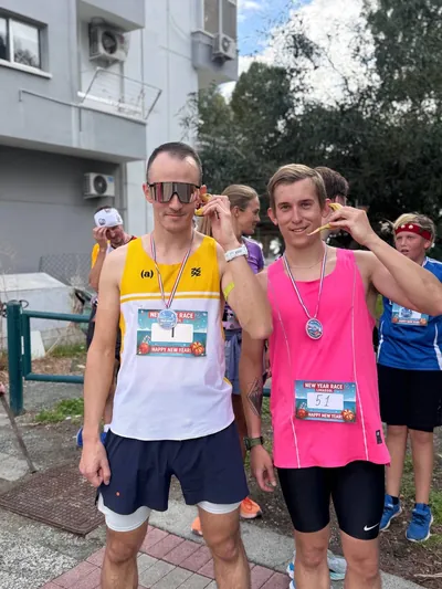 Two runners in race vests holding up their finisher medals.