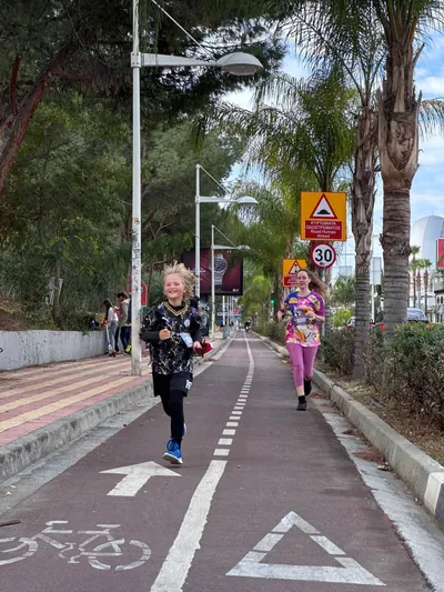 A child running on the bike path with another runner following, palms behind.