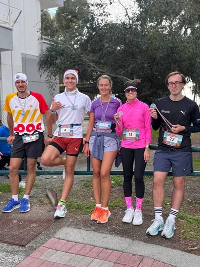 Five runners in Santa hats with their finisher medals.