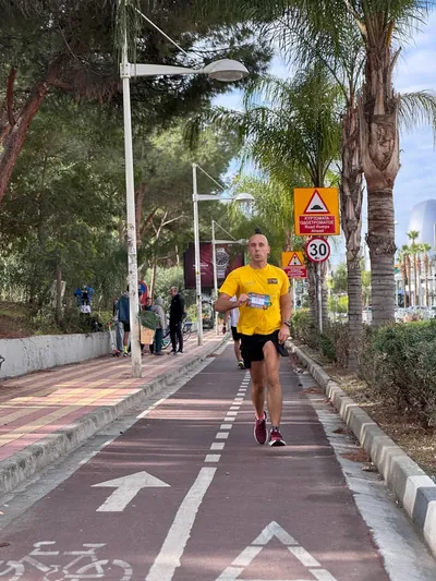 A runner in yellow on the palm-lined coastal path.