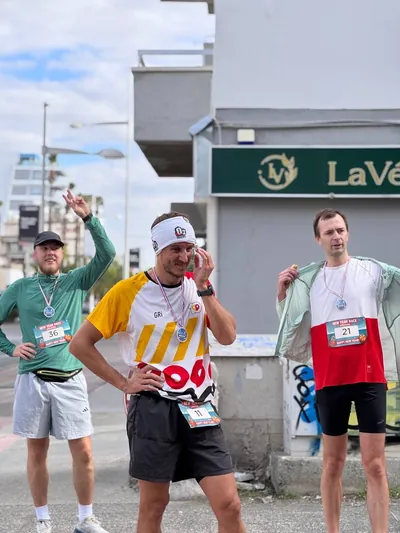 Three runners with medals celebrating after the finish.